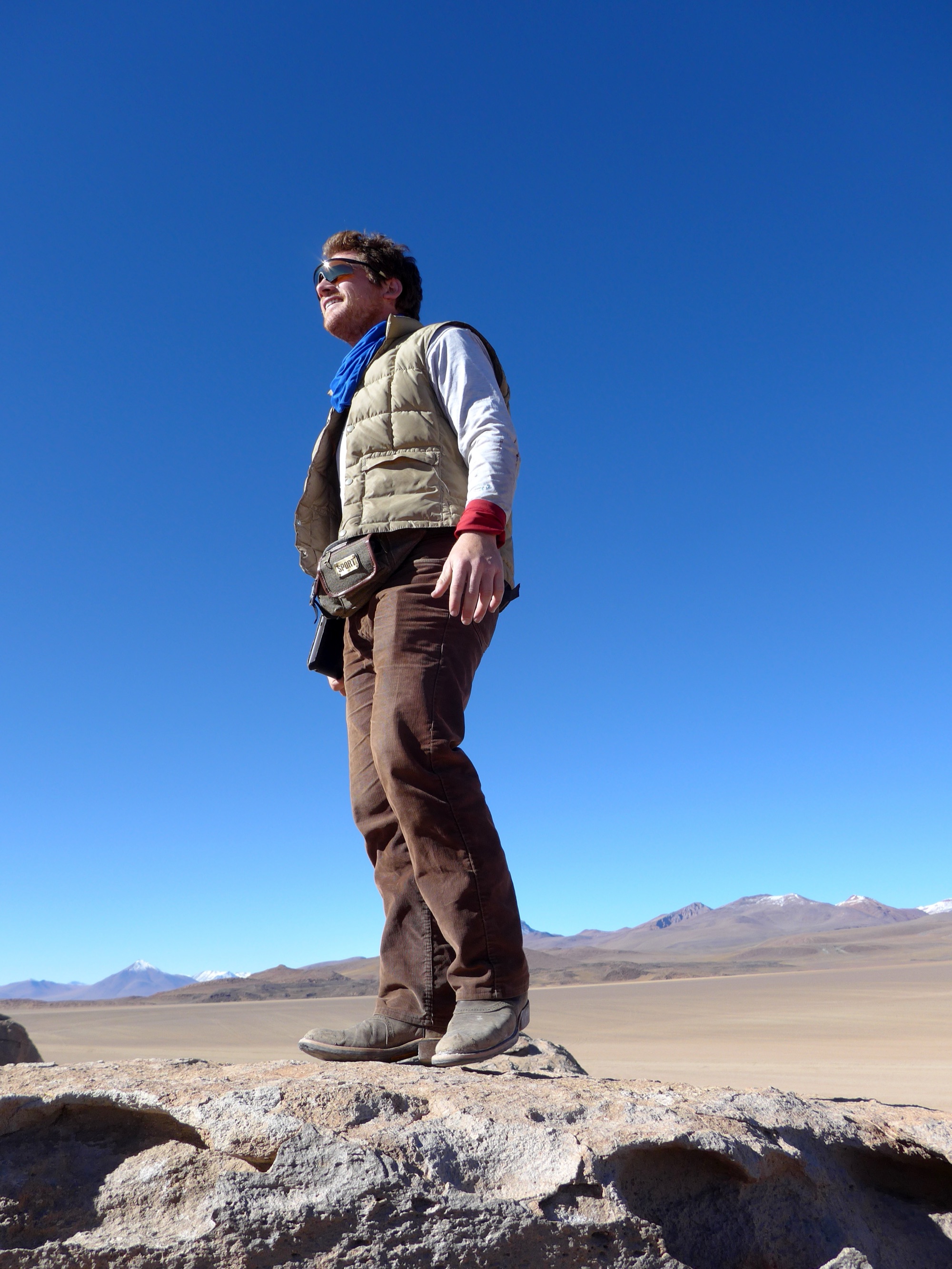 Sonny standing on a rock under a deep blue sky, mountains on the horizon